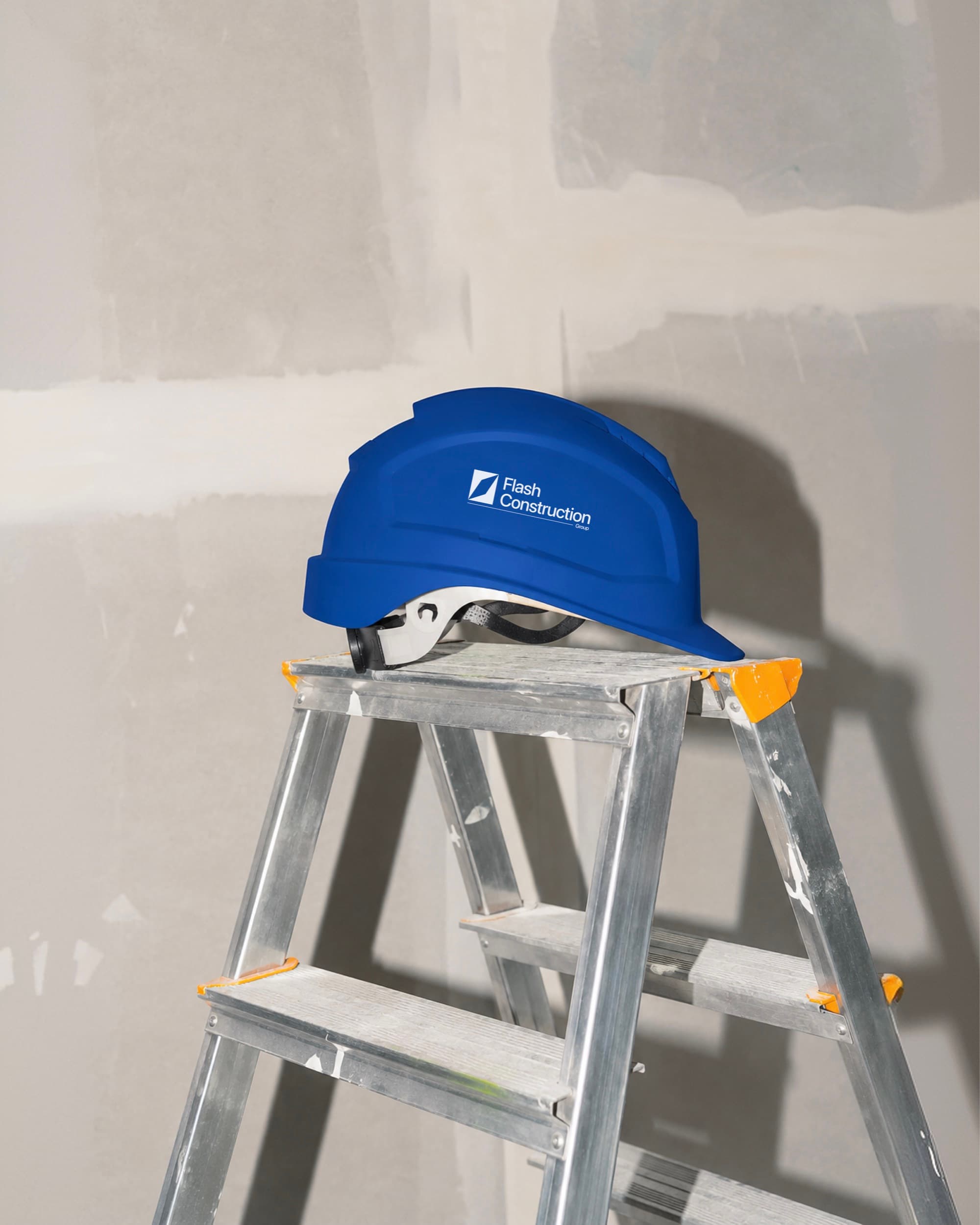 Capacete azul com a marca da Flash Construction Group aplicada, apoiado em uma escada de obra.