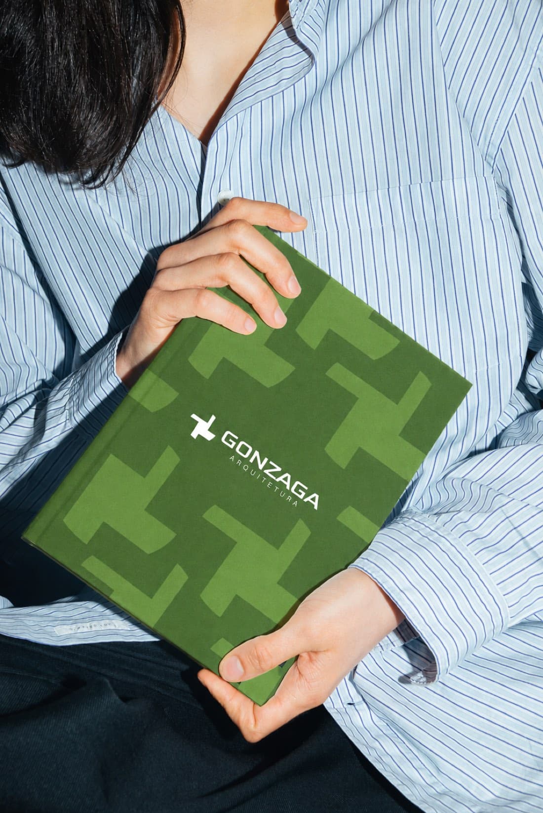 Livro de marca da Gonzaga em capa verde com o símbolo em cruz repetido em padronagem.